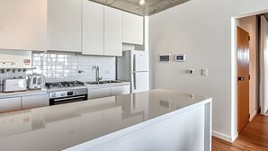Een moderne keuken met witte kasten, een groot eiland, een gasfornuis en een koelkast.