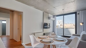 Een moderne eetruimte met een ronde tafel, witte stoelen en een stadszicht door grote ramen.