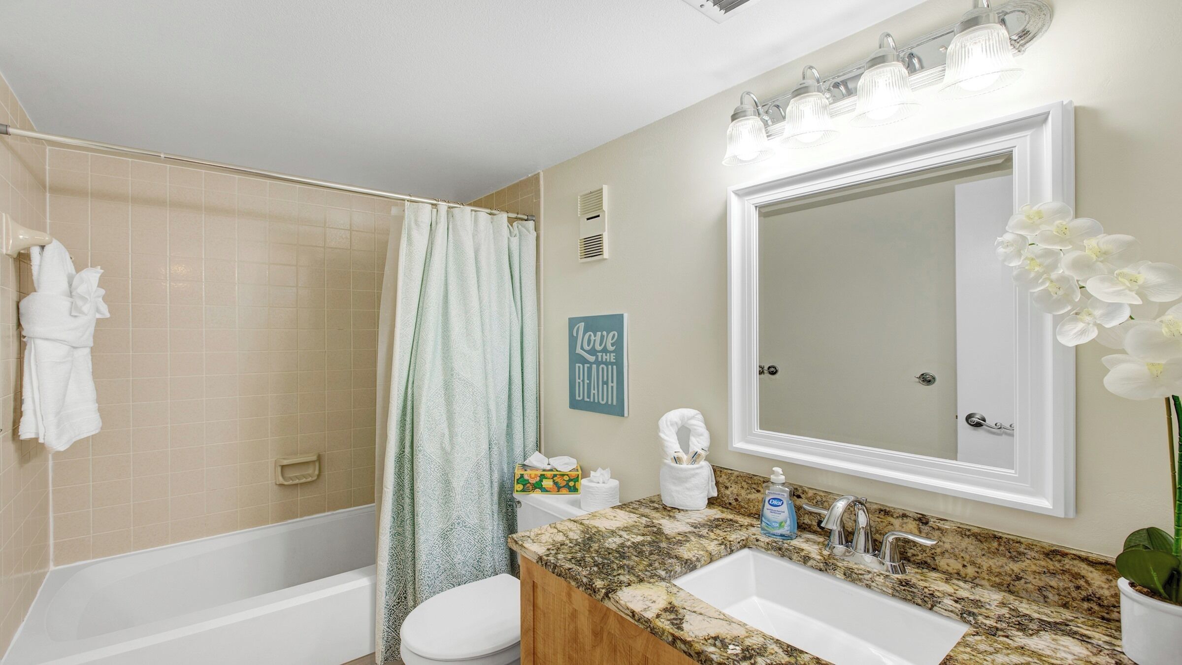 Une salle de bain avec une baignoire, des toilettes, un lavabo et un grand miroir.