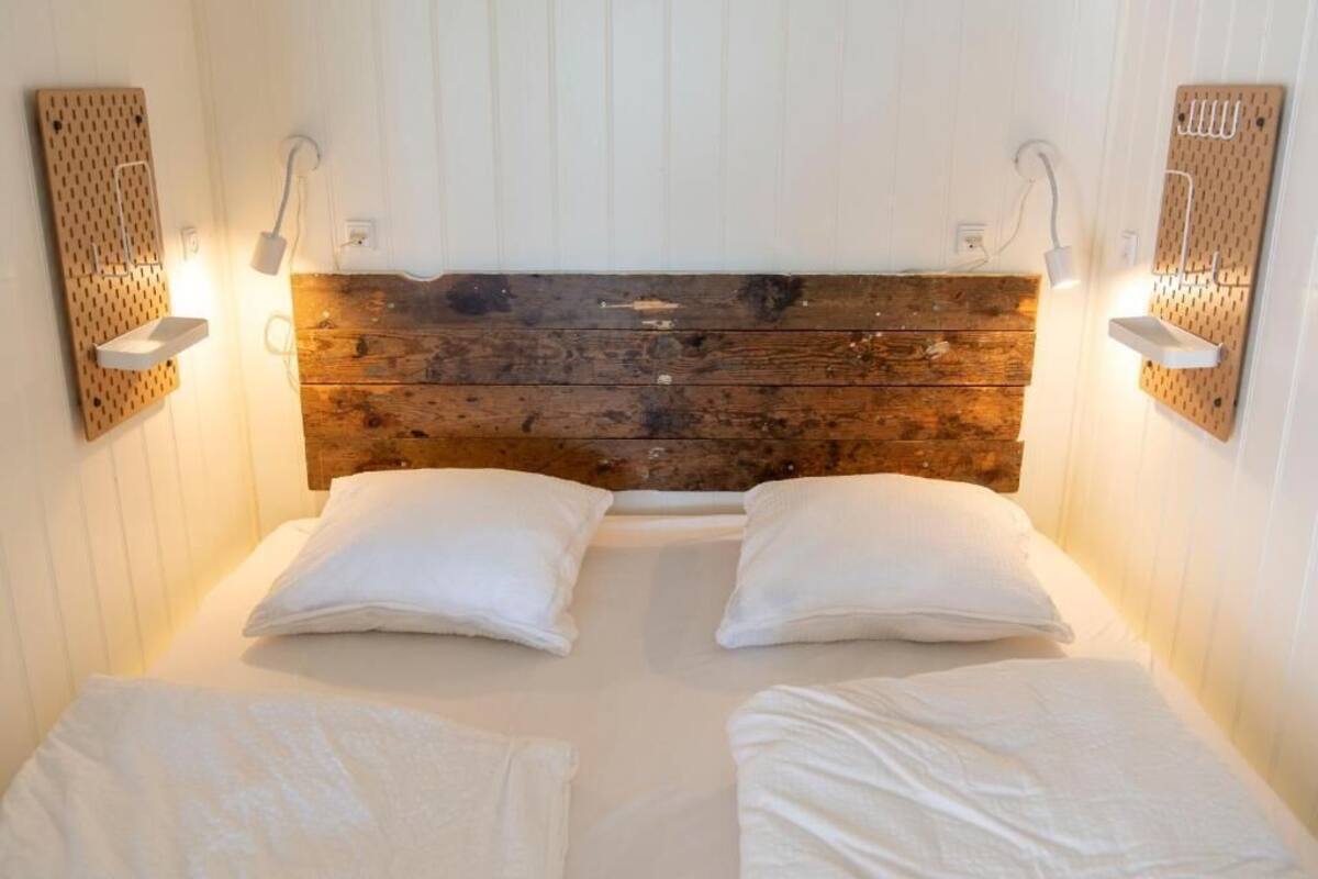Ein Zimmer mit einem Holzkopfteil, zwei weißen Kissen und Nachttischen mit Wandlampen.