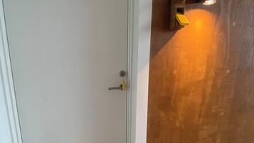 A door with a handle and a light fixture mounted on the wall beside it.
