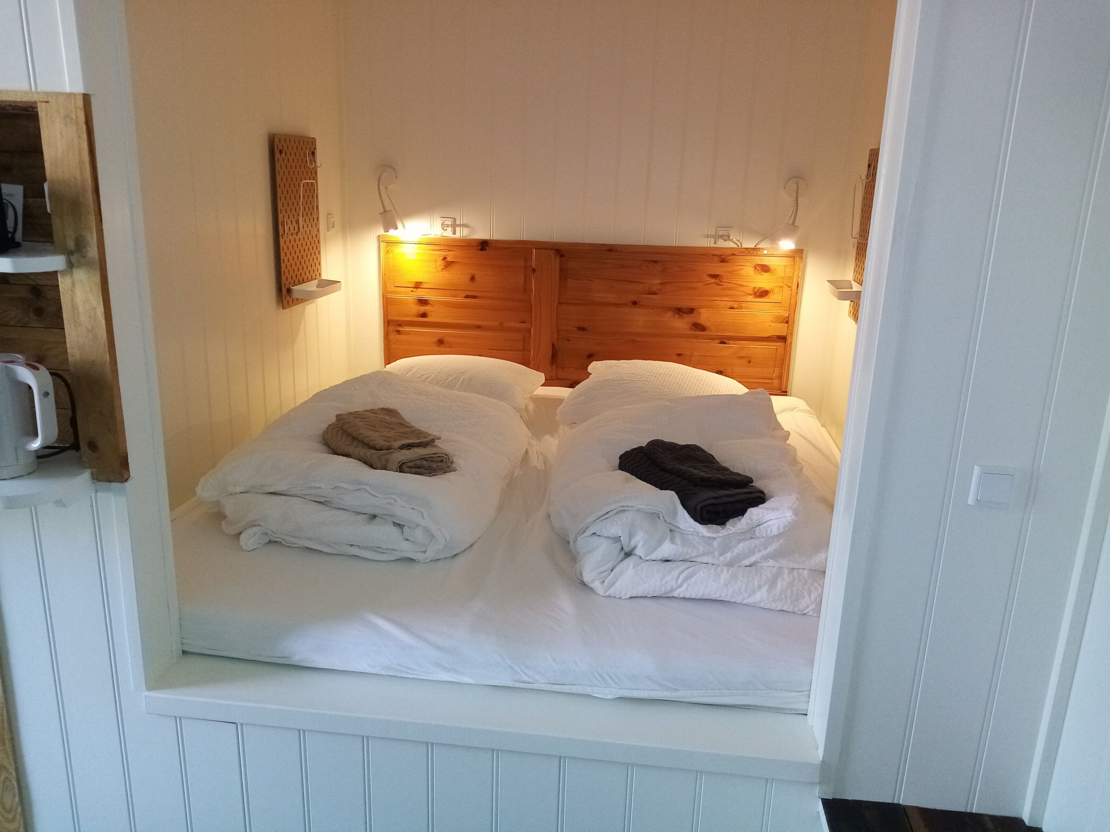 Ein gemütliches Zimmer mit zwei Betten, einem Holzkopfstück und Wandleuchten.