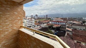 Un balcone con vista su un paesaggio urbano, che include edifici e una catena montuosa all'orizzonte.