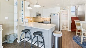 A modern kitchen with white cabinets, stainless steel appliances, and a central island with bar stools. - Ocean Mile I-4 - Beach Front, Swimming Pool, Beach Gear Included! (St George Island)