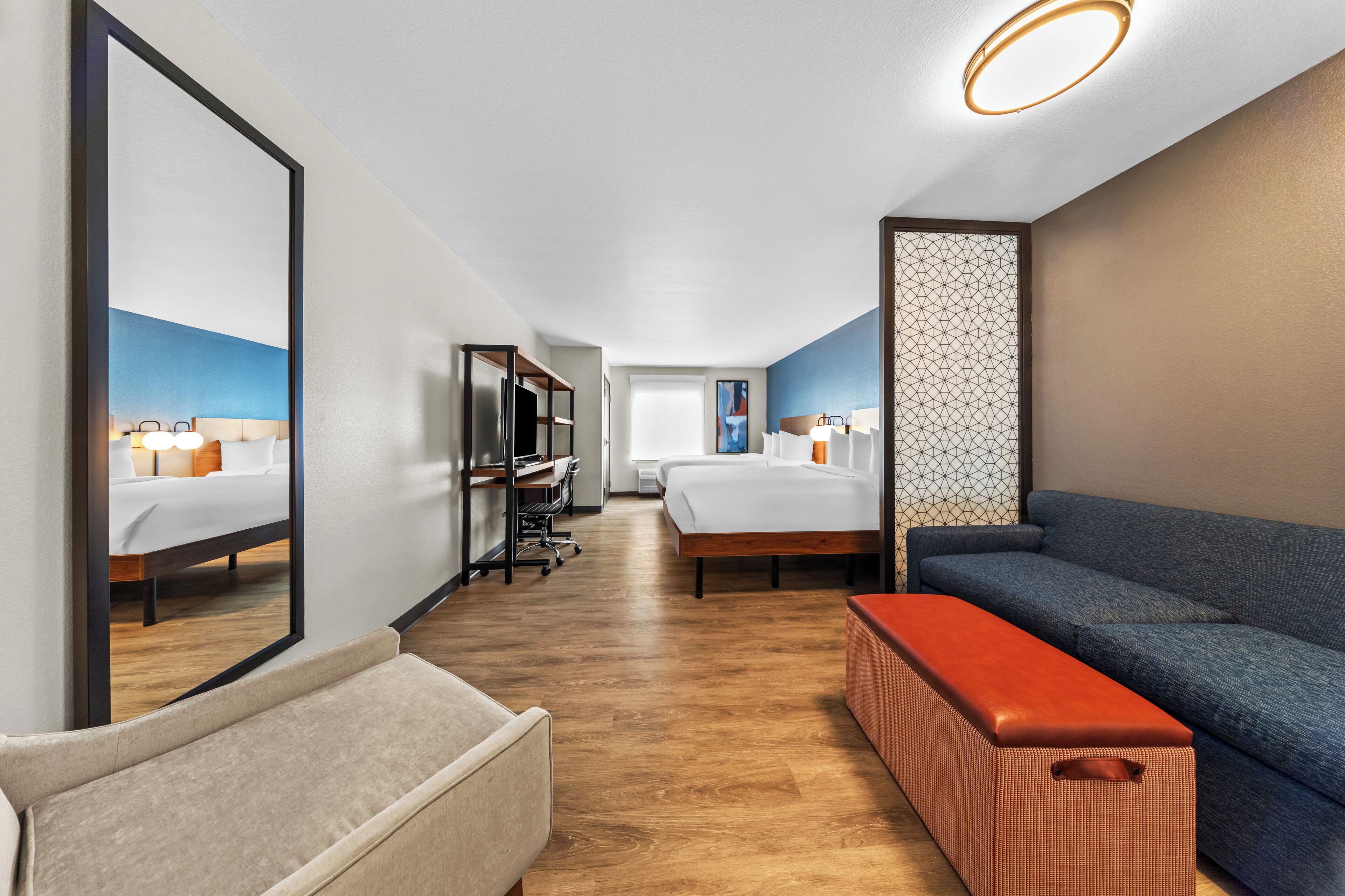 Una habitación de hotel con una cama grande, un escritorio con una silla, un sofá y un pequeño otoman.