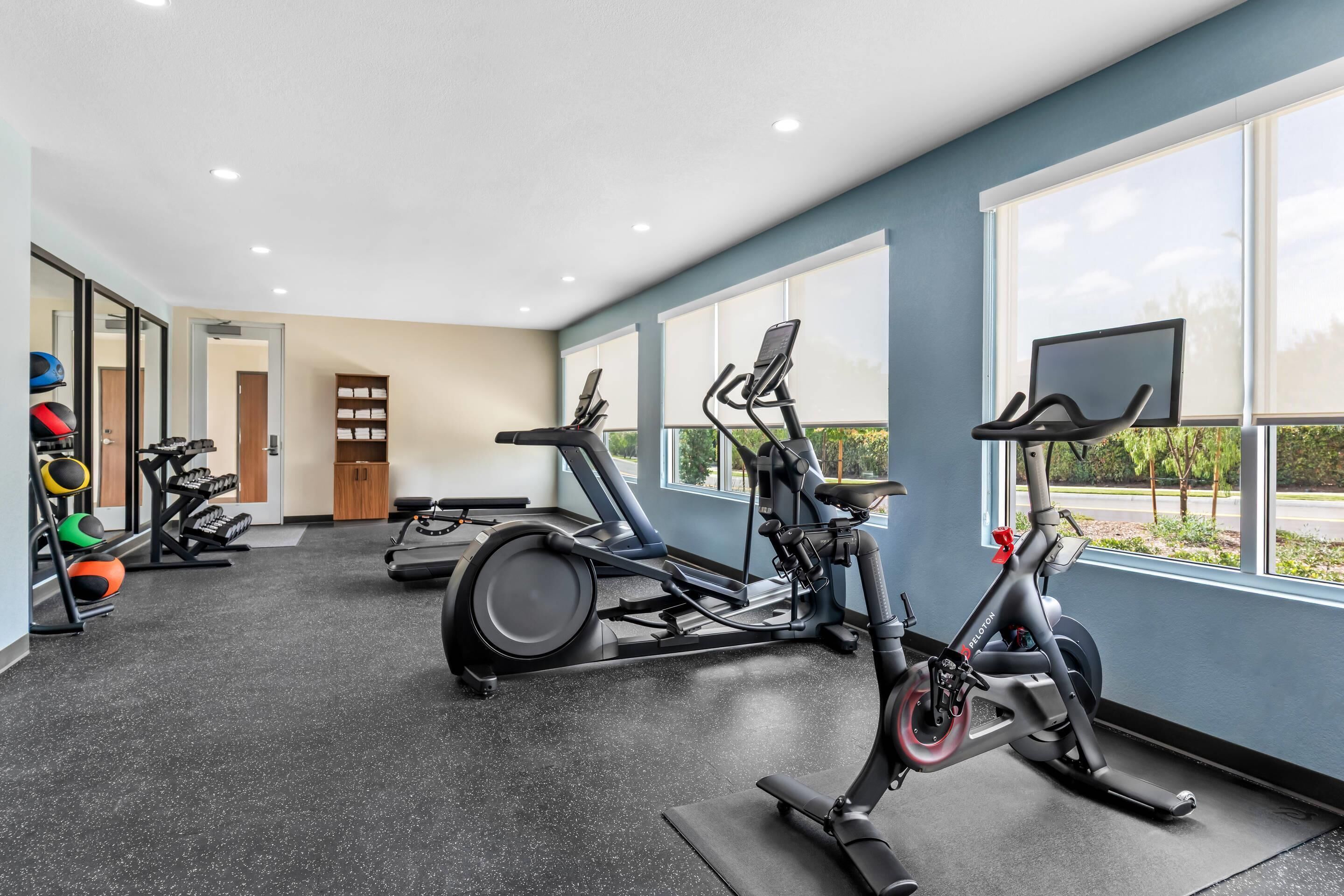 Un gimnasio con equipo de ejercicio, ventanas amplias y vistas al exterior.
