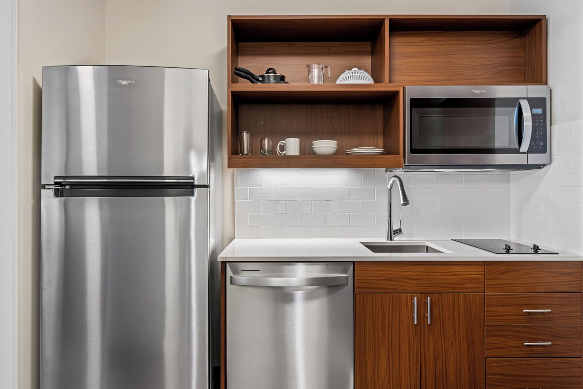 Una cocina moderna con un refrigerador de acero inoxidable, microondas integrado y armarios de madera.