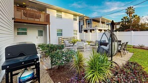 A backyard with a barbecue grill, outdoor furniture, and a swing chair.