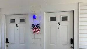 Two white doors with numbers 6 and 5, a small American flag decoration, and a blue lantern above the door with number 6.
