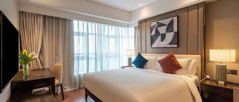 A modern hotel room with a large bed, a desk, and a TV.