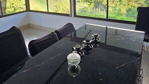 A modern dining area with a glass table, black chairs, and a pendant light.