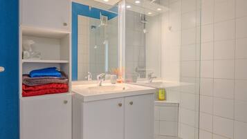 A modern bathroom with a white sink, mirror, and glass shower enclosure.