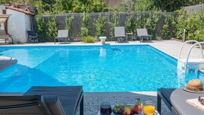 A swimming pool with lounge chairs and a table with fruits and drinks. - Appartement Sky (Peraia)