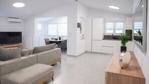 A modern apartment with a living room, dining area, and kitchen. - Appartement Sky (Peraia)