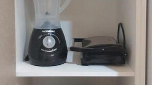 A kitchen with a blender, a kettle, and a slow cooker on shelves. - Studio Equipado em Apartamento Clube com Academia no Centro de Curitiba MID Home (Centro Curitiba)