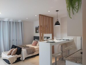 Une chambre à coucher moderne avec un lit, une table de chevet et un petit coin salon.
