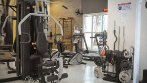 A gym with various exercise equipment, including a squat rack, treadmills, and weight machines. - Studio Equipado em Apartamento Clube com Academia no Centro de Curitiba MID Home (Centro Curitiba)