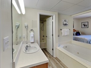 A bathroom with a sink, a hairdryer, a shower, and a bathtub.