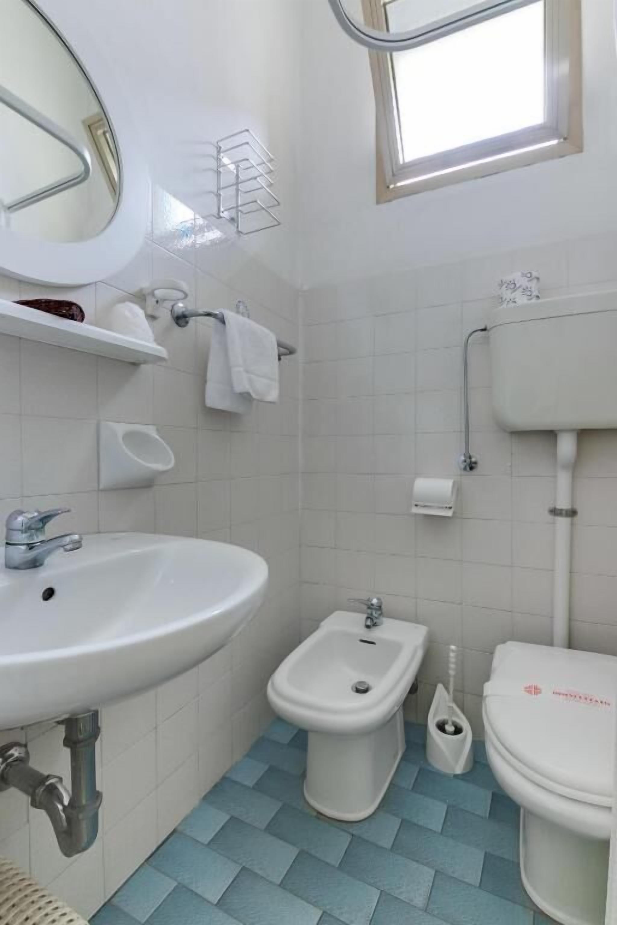 Un baño con lavamanos, bidé, inodoro y ventana.