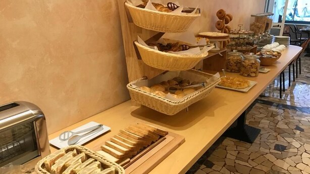 A buffet setup with multiple baskets of bread and pastries, a toaster, and a tray of sliced bread. - Hotel Villa Merope (Rimini)