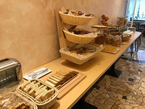 Un montaje tipo bufé con varias cestas de pan y bollería, un tostador y una bandeja de pan en rebanadas.