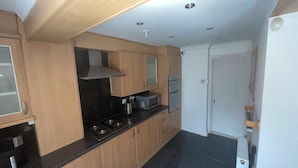 Een moderne keuken met houten kastjes, een gasfornuis, een magnetron en een oven.