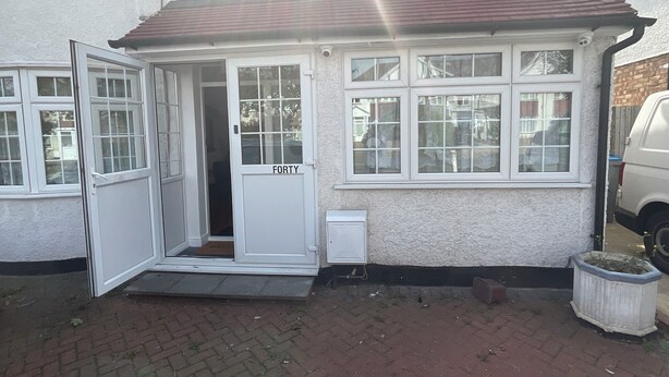 Een wit huis met een deur waarop 'FORTY' staat en een kleine opstap naar de ingang.