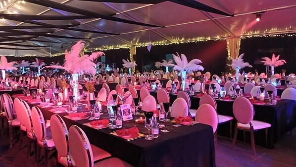 A banquet hall with tables set for a formal event, featuring white chairs, black tablecloths, and decorative centerpieces. - Phakalane Golf Estate Hotel & Convention (Gaborone)