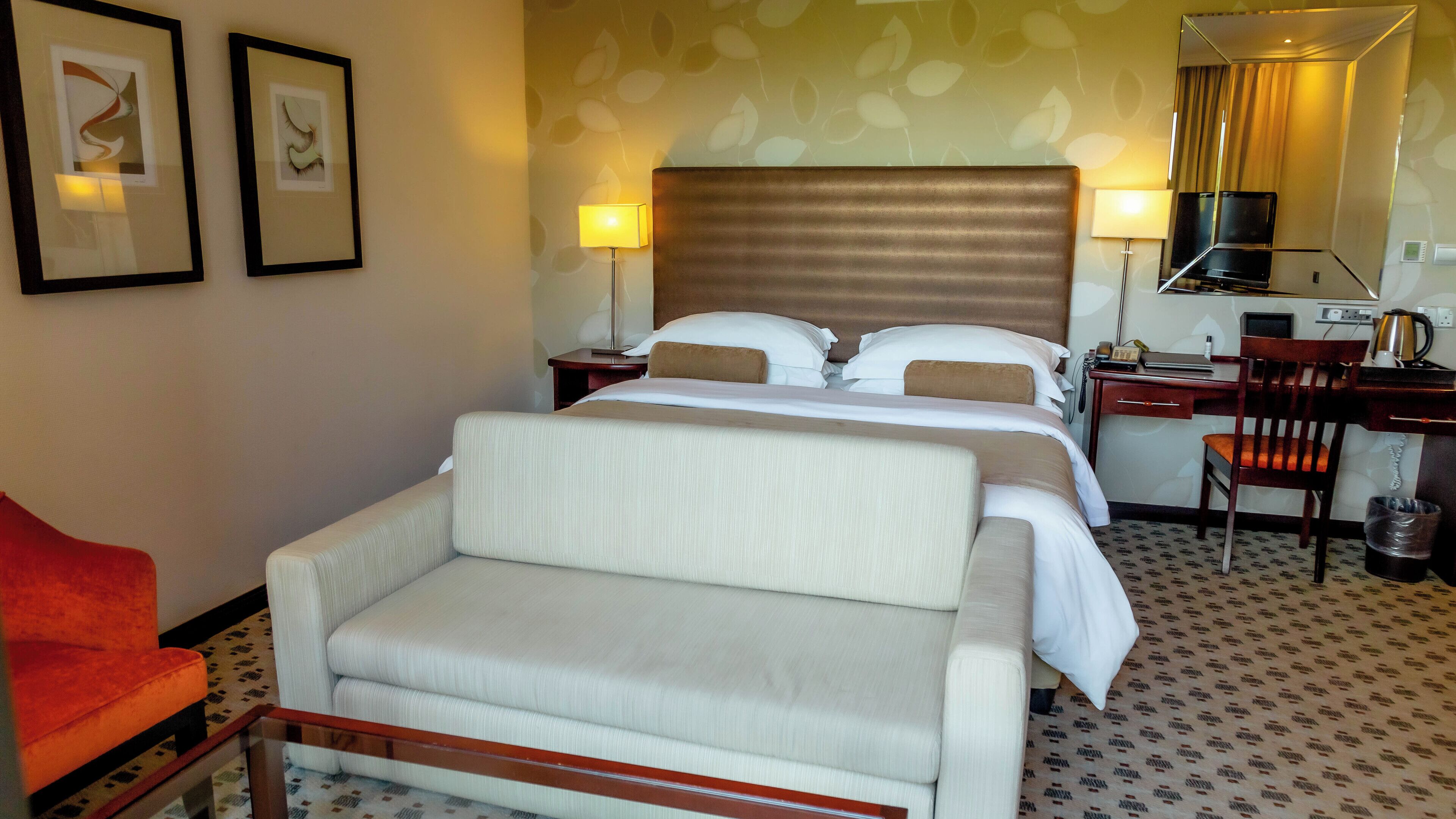 Una habitación de hotel con cama, escritorio, silla y sofá.