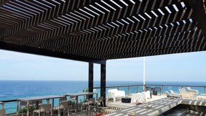 A rooftop terrace with a view of the ocean, outdoor seating, and a modern ceiling design. - Paradise Tamarindo (Sabana de Guacuco)