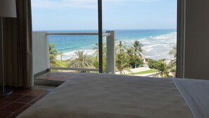 A hotel room with a large window overlooking a beach and ocean. - Paradise Tamarindo (Sabana de Guacuco)