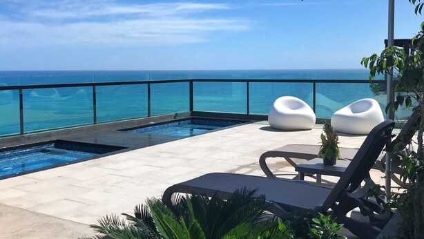 A poolside area with lounge chairs, a small pool, and a view of the ocean. - Paradise Tamarindo (Sabana de Guacuco)