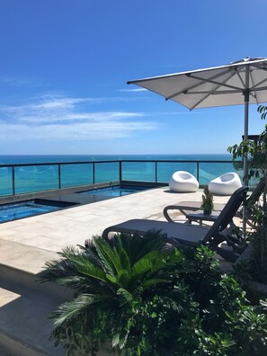 A poolside area with lounge chairs, a small pool, and a view of the ocean. - Paradise Tamarindo (Sabana de Guacuco)