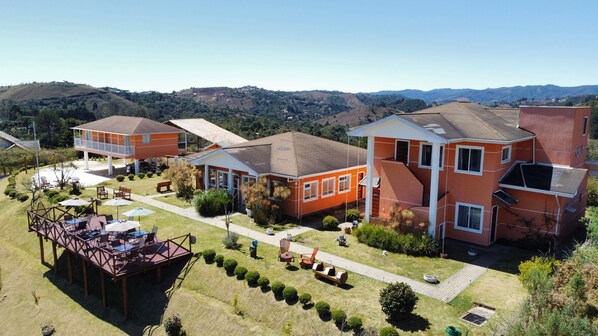 Un barrio residencial con varias casas, un patio con mobiliario exterior y vistas a las colinas circundantes.
