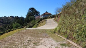 A rural road leading to a house with a tiled roof, surrounded by greenery and hills. - Vila Chantal by Rivaj  (Campos do Jordão)