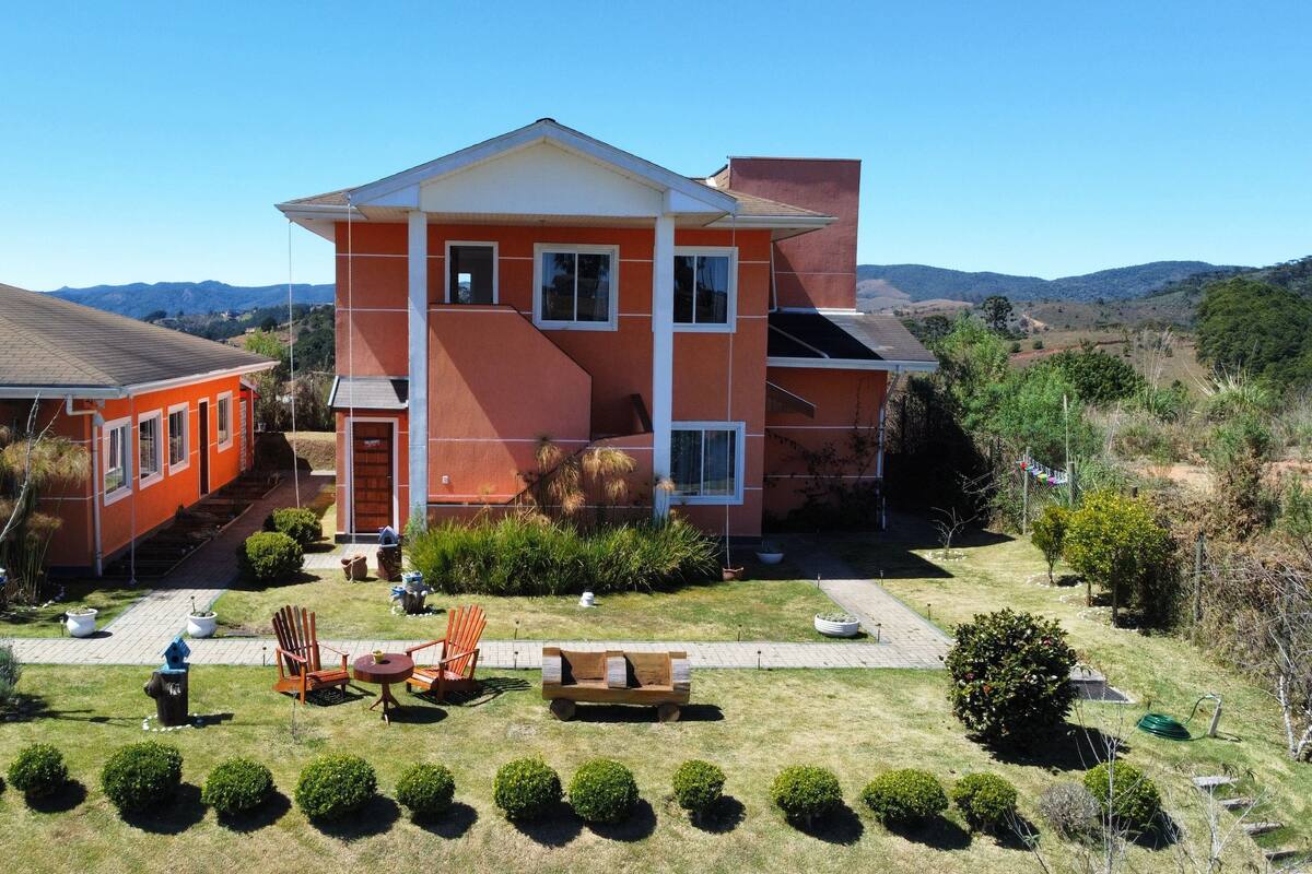 A two-story building with a red and white exterior, a front porch, and a well-maintained lawn with trimmed bushes.