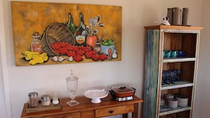 A wooden console table with various kitchen items and a decorative painting above it. - Vila Chantal by Rivaj  (Campos do Jordão)