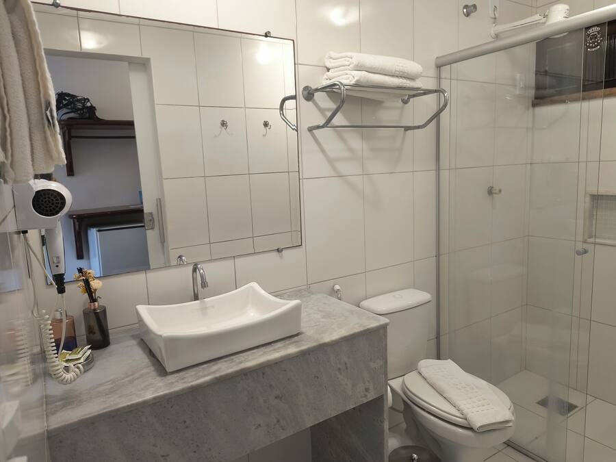 Een moderne badkamer met een marmeren wastafel, toilet, douchecabine van glas en een handdoekrek.