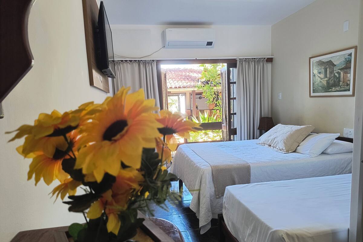 Habitación de hotel con dos camas, un televisor montado en la pared y un cuadro.