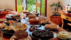 A buffet table with various baked goods and desserts. - Pousada guaratiba (Prado)