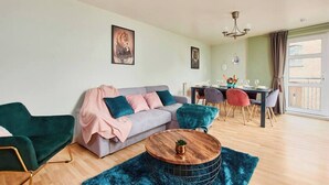 Un salon moderne comprenant un canapé, une table basse ronde et un coin repas avec des chaises et une table.