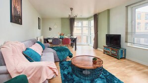 Un salon comprenant un canapé, une table basse et un téléviseur. Il y a également un coin repas avec une table et des chaises.