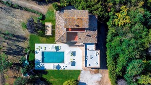 En vy från ovan av ett hus med en swimmingpool, en uteplats och en trädgård.