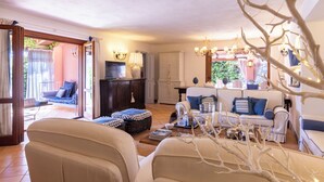 A cozy living room with a sofa set, a television, and a dining area with a table and chairs. - Villa Bambù 9+2, Emma Villas (Maratea)