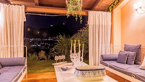 A cozy outdoor seating area with a view of a cityscape at night. - Villa Bambù 9+2, Emma Villas (Maratea)