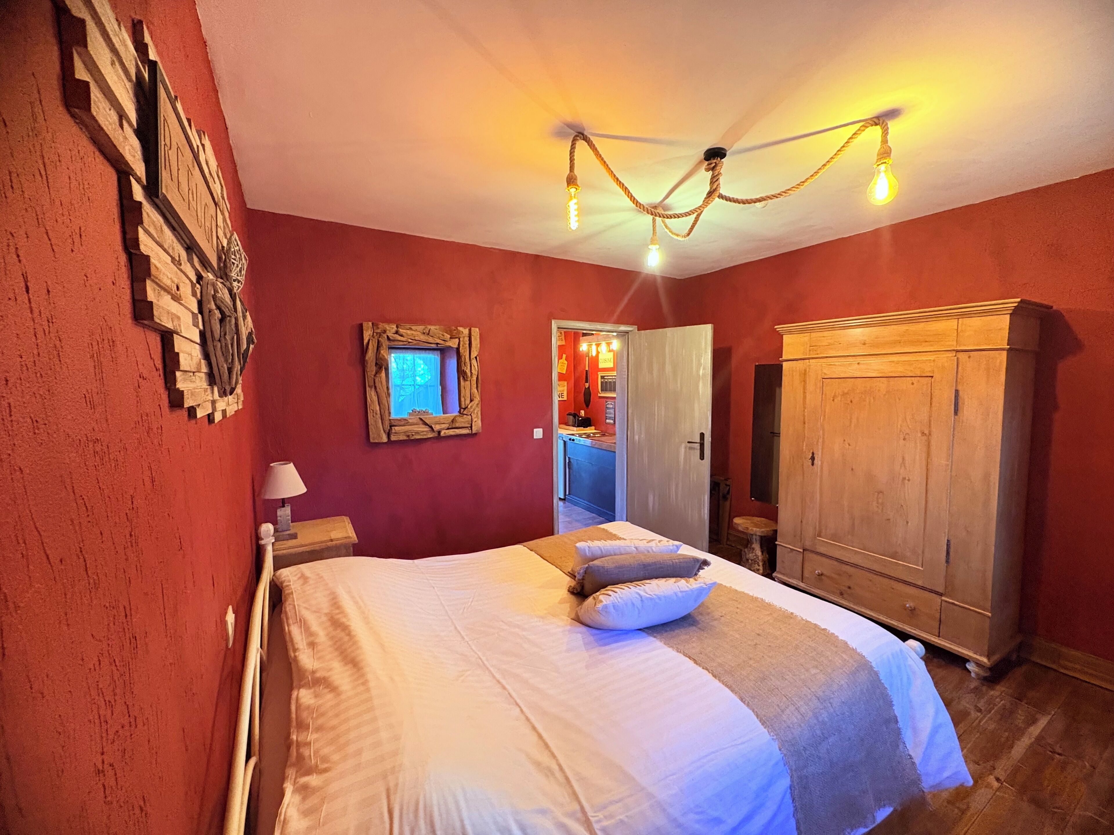 A bedroom with a bed, wooden wardrobe, and a rustic wall decoration.