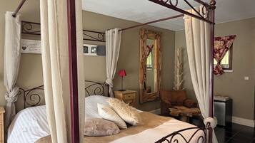 A four-poster bed with a canopy, a bedside table, a mirror, and a small nightstand.