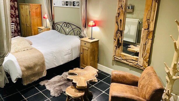 A bedroom with a bed, wooden nightstands, a mirror, and a chair. - Comme à la ferme (Durbuy)