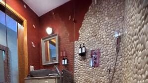 A bathroom with a pebble-patterned floor, a wooden dresser, a mirror, and a shower with a pebble wall. - Comme à la ferme (Durbuy)