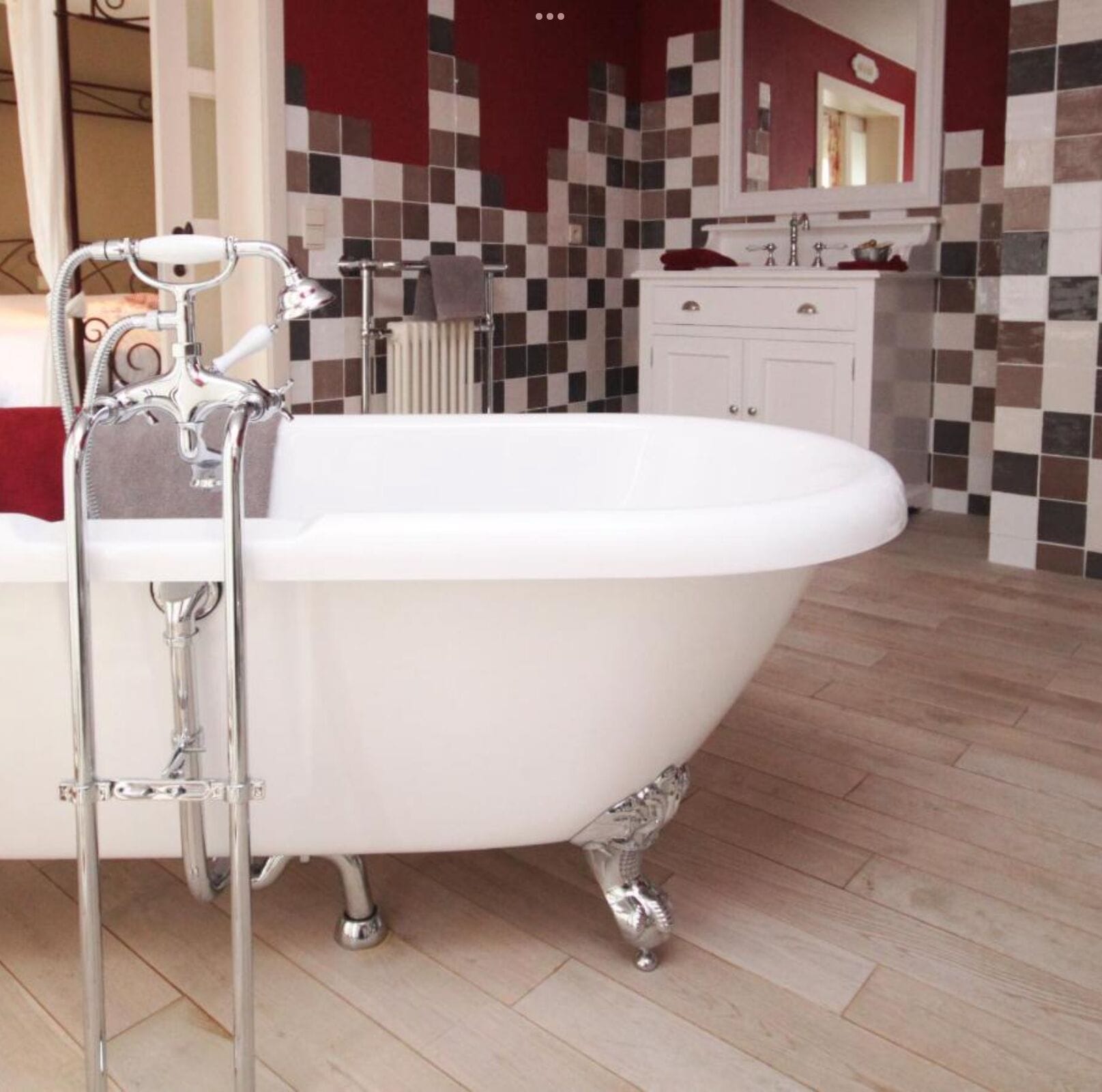 Un baño con una bañera independiente, un lavabo blanco y un salpicadero de azulejos.